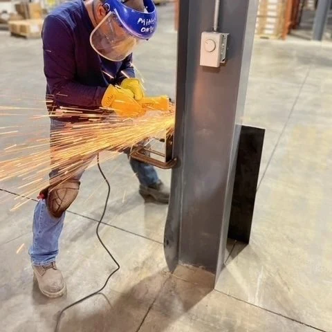 Welder grinding a fabricated structural steel column in the Capital M shop